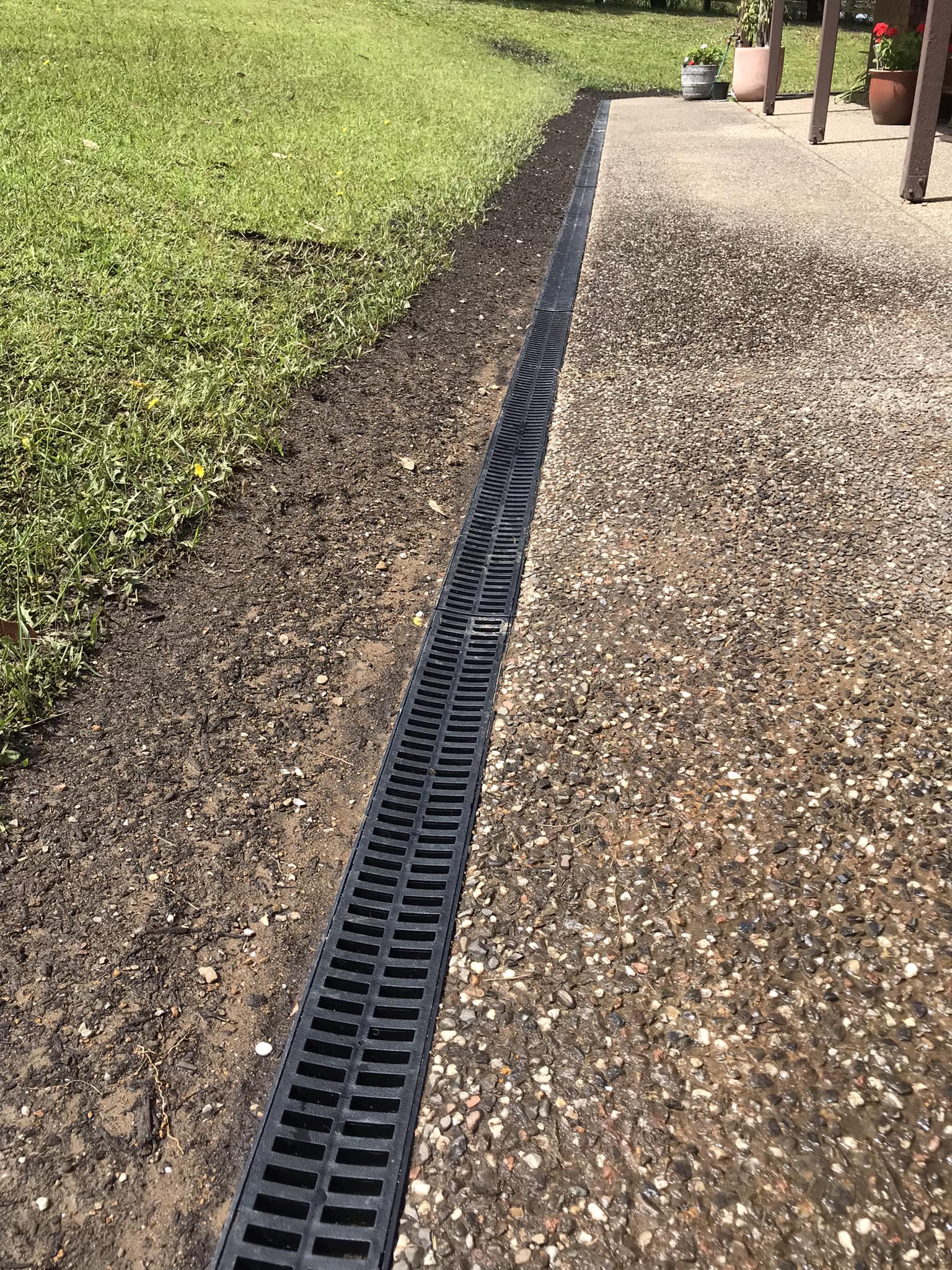 A finished channel drain run along the edge of a driveway, backfilled and cleaned up